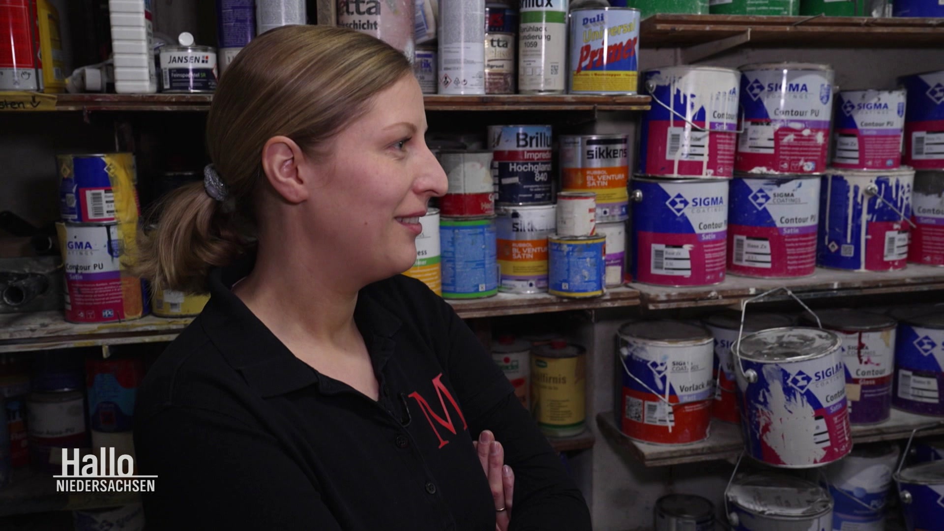 Malermeisterin Friederike Mönnig aus Vechta steht vor einem Regal mit Farbeimern. © Screenshot 