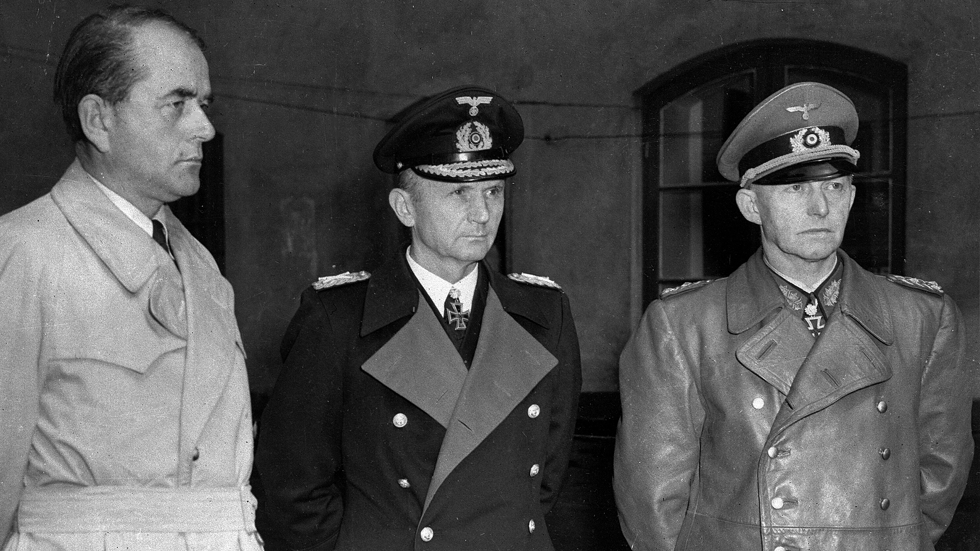 Mitglieder der deutschen Regierung "Dönitz":  Minister für Rüstung und Kriegsproduktion Albert Speer (links), Großadmiral Karl Dönitz (Mitte) und General Alfred Jodl warten in einem Hof ​​in Flensburg nach ihrer Festnahme durch britische Truppen am 24. Mai 1945. © picture alliance / ASSOCIATED PRESS 