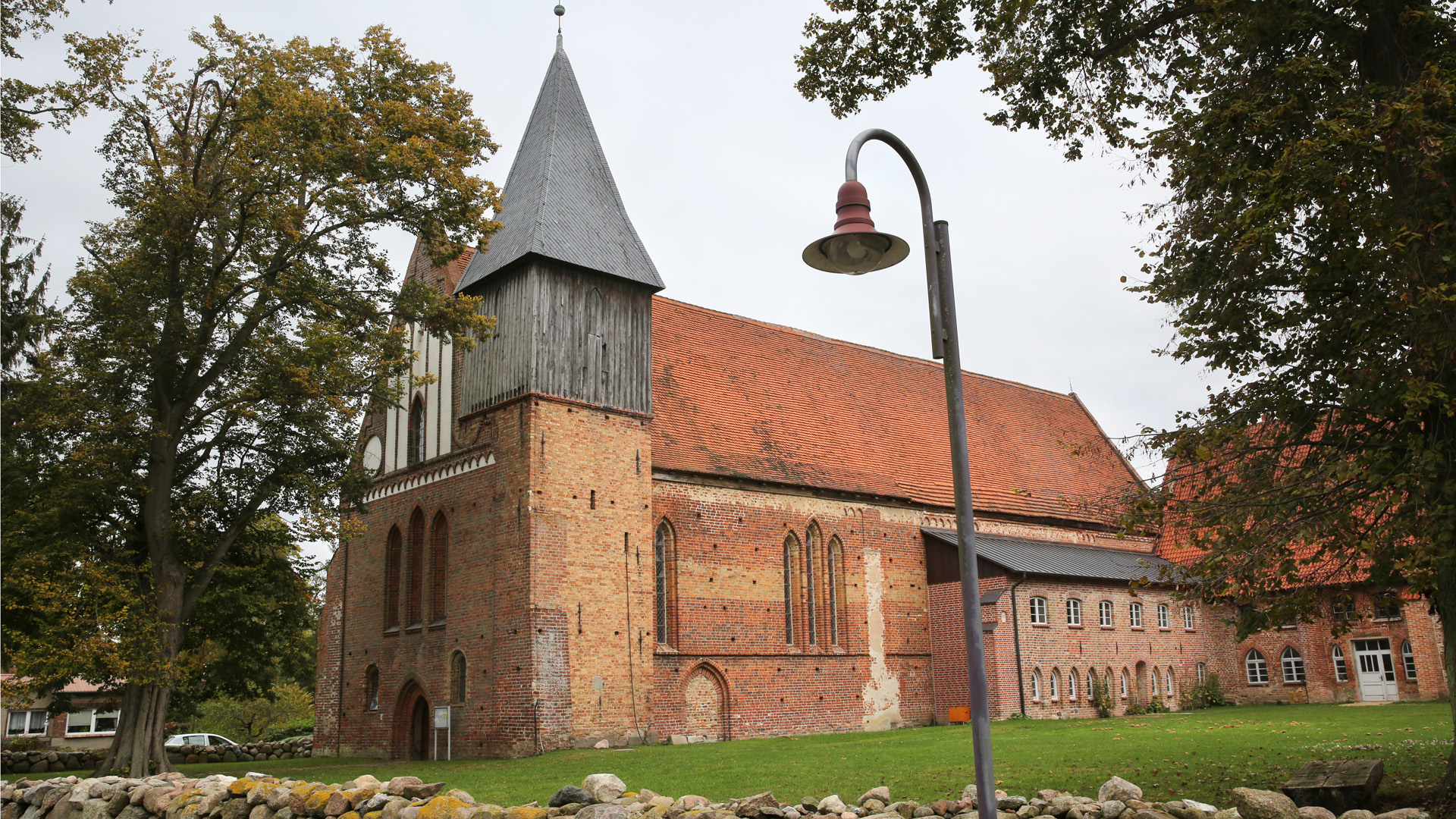 Die Backsteinkirche des ehemaligen Klosters in Rühn, Mecklenburg-Vorpommern von Eichen umrahmt. © dpa Foto: Bernd Wüstneck