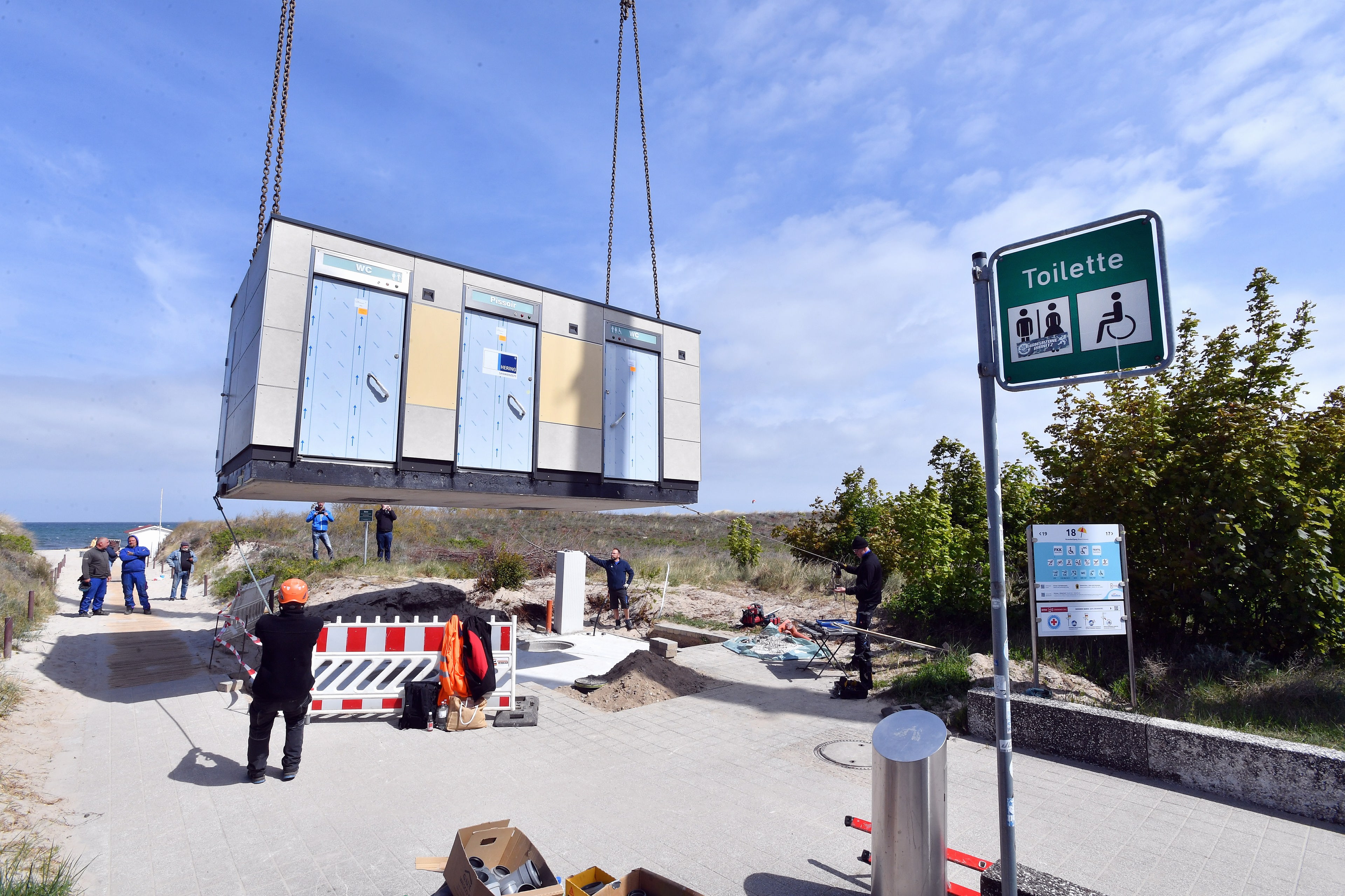 Ein Toilettenhäuschen wird an einem Kran an der Promenade in Warnemünde herunter gelassen. © Joachim Kloock Foto: Joachim Kloock