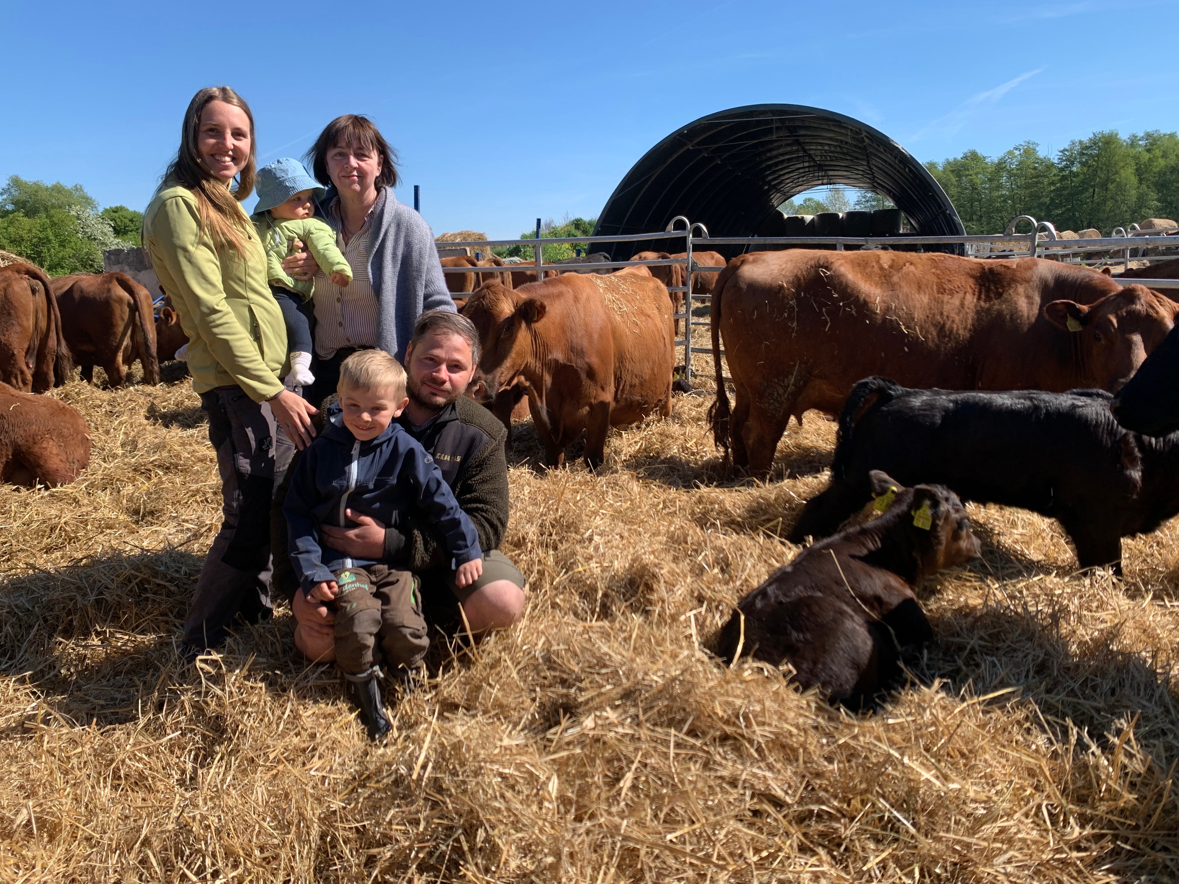 Drei Generationen der Familie Wartmann stehen auf Stroh in einem Außengatter ihrer Rinderhaltung. © NDR Foto: Silke Müller