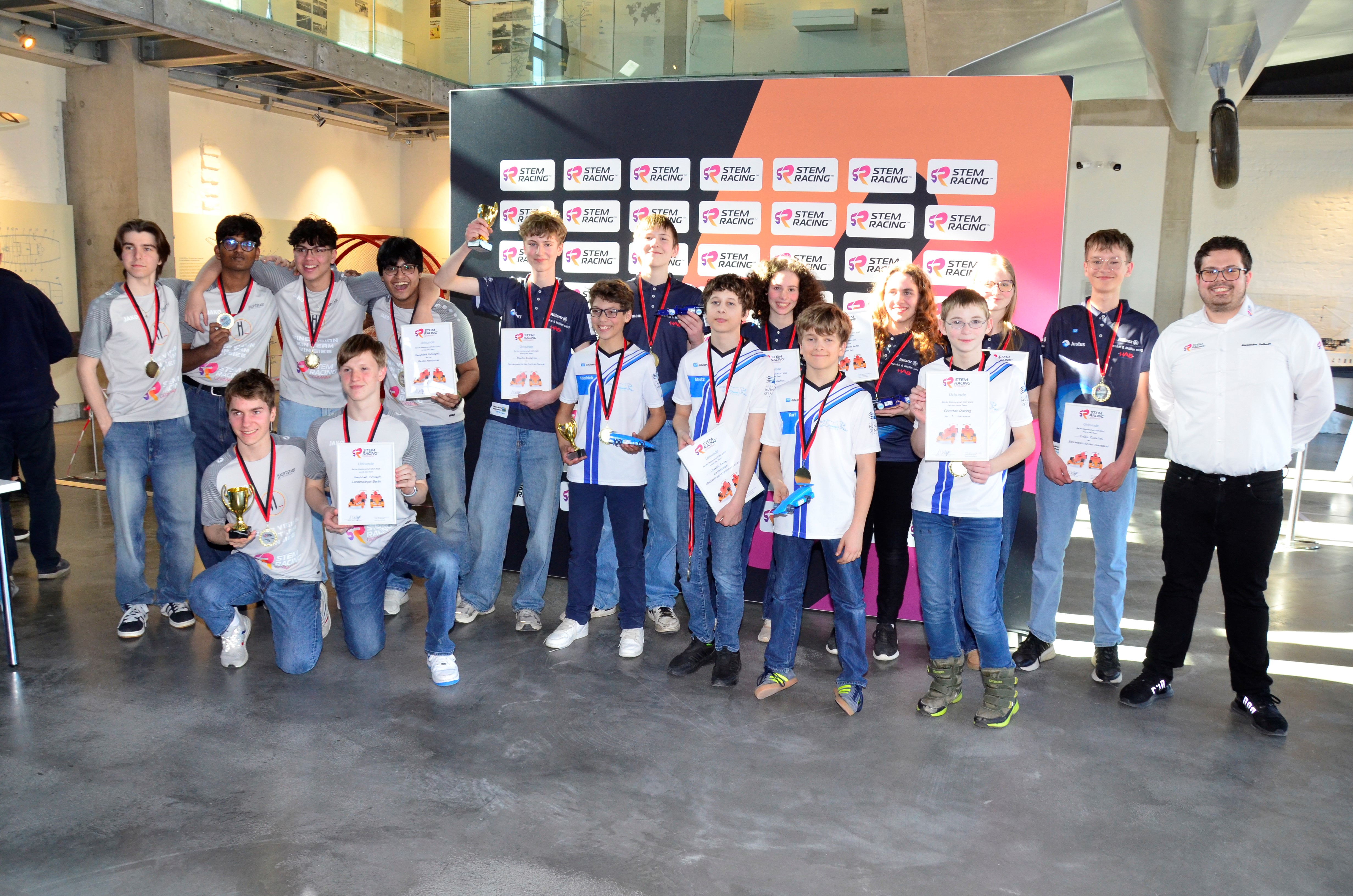 16 Jugendliche und ein Erwachsener posieren als Sieger für ein Foto. Sie tragen dabei teilweise Teamkleidung. © SETeC gGmbH Foto: SETeC gGmbH