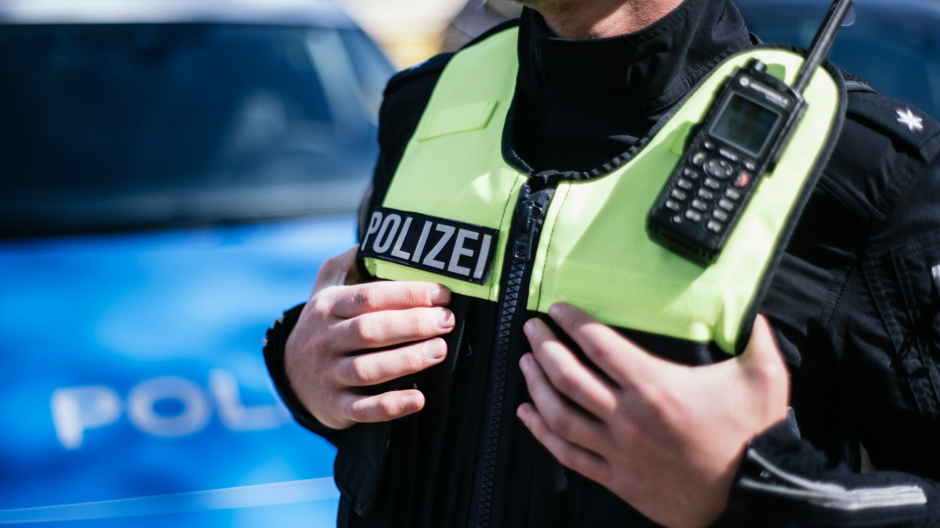 Ein Polizist, der hat seine Hände unter die Schutzweste der Uniform gesteckt hat. © NDR Foto: Julius Matuschik