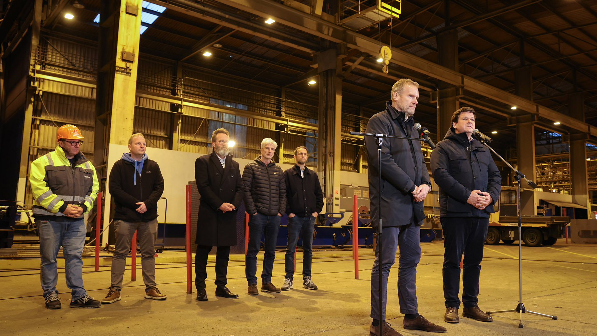 Flensburg: Die vorläufigen Insolvenzverwalter Christoph Morgen (r) aus der Kanzlei Brinkmann+Partner und Hendrik Gittermann aus der Kanzlei Reimer Rechtsanwälte sprechen bei einer Pressekonferenz in einer Werfthalle der FSG nach einer Mitarbeiterversammlung. © dpa Foto: Christian Charisius