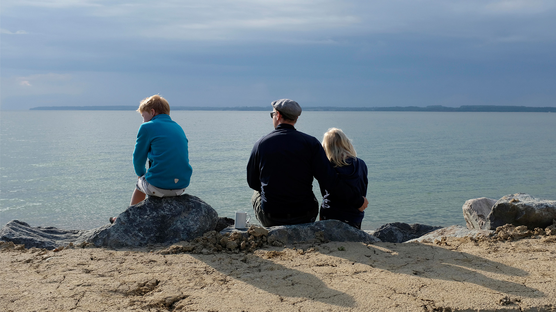 Vater mit Sohn und Tochter auf einem Felsen an der Ostsee sitzend. © picture alliance / Westend61 Foto: Gianna Schade