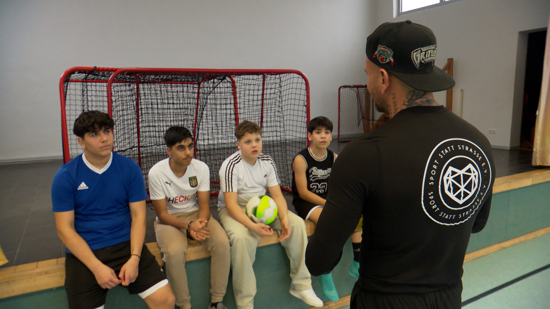 Jugendliche haben in einer Turnhalle eine Besprechung mit dem Trainer. © NDR 