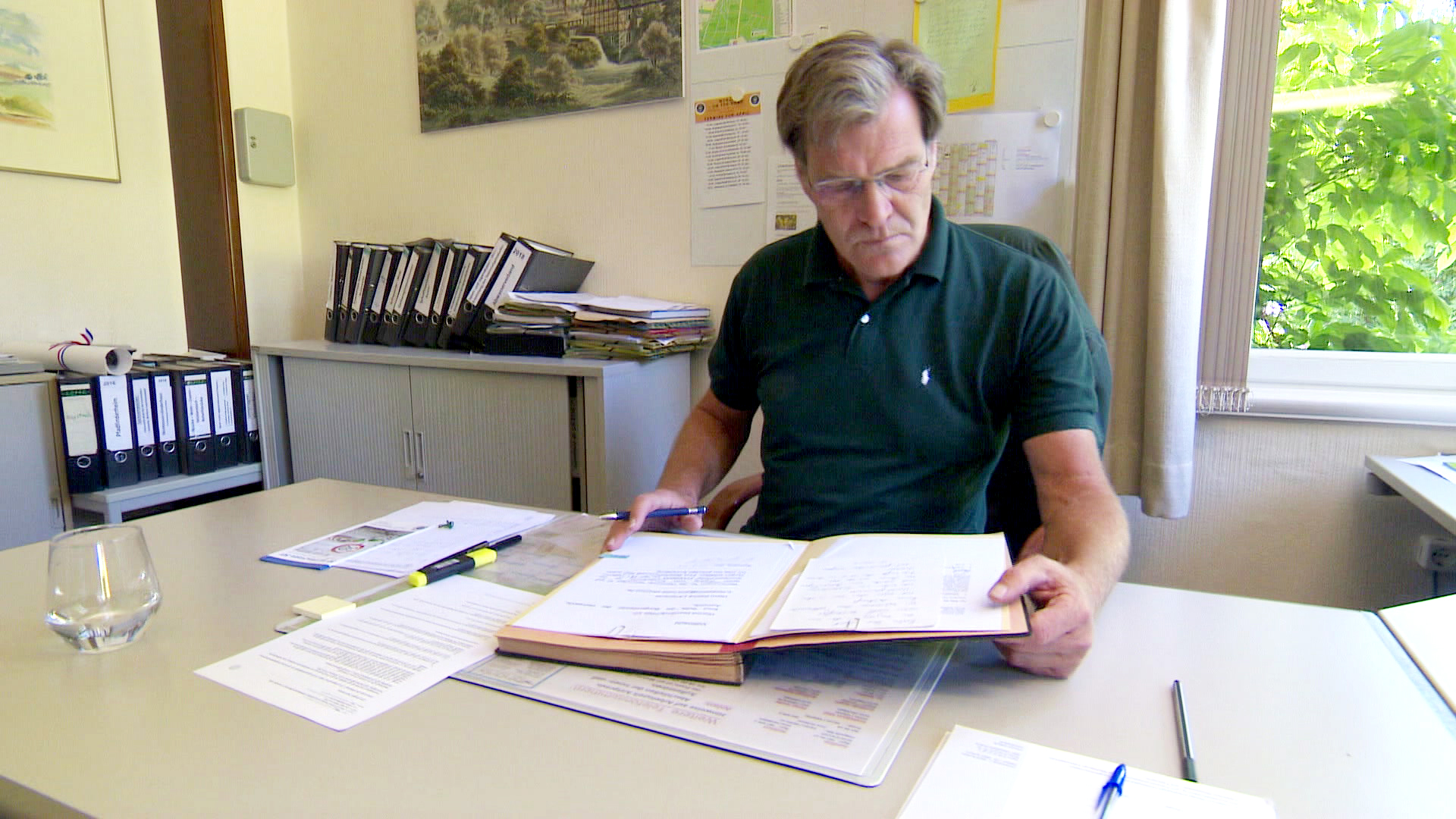Knut Suhk sitzt vor einem Ordner in seinem Büro. © NDR Foto: Hauke von Hallern